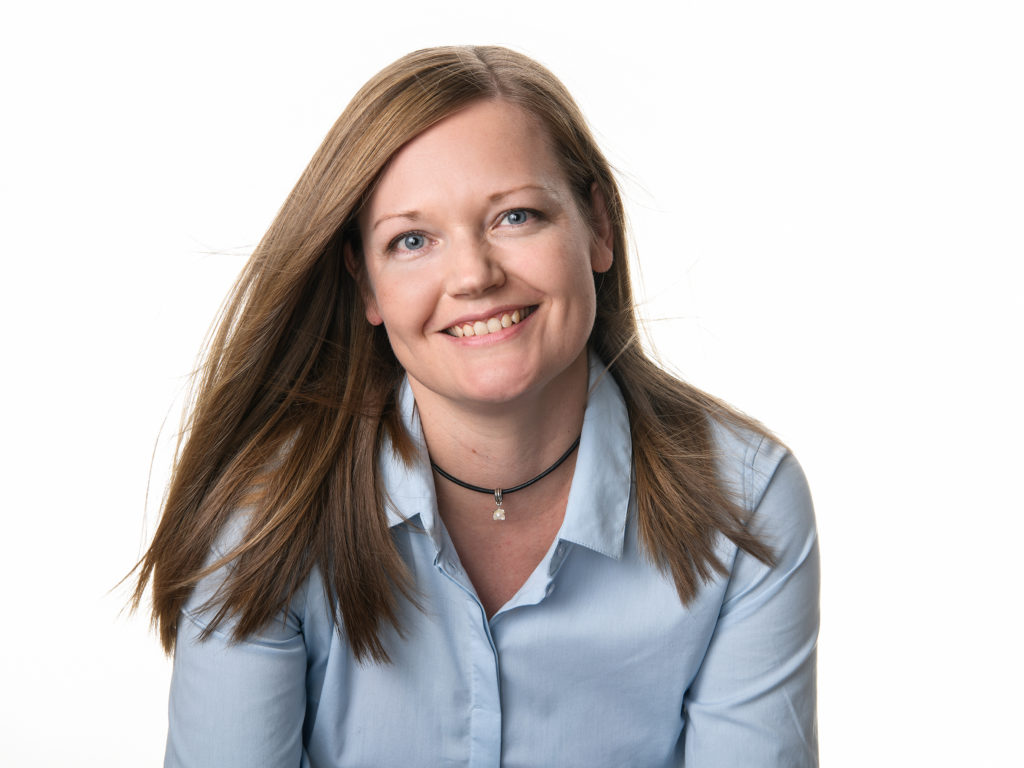 Ruskeahiuksinen nainen sinisessä kauluspaidassa